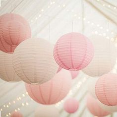 pink and white paper lanterns hanging from the ceiling in a marquee with string lights