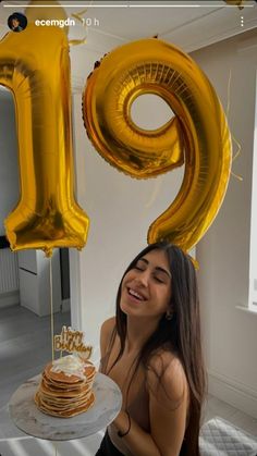 a woman sitting in front of a cake with the number nine on it and gold balloons