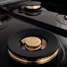 closeup of the knobs on an electric stove with gold trim and black burners