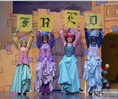 the children are dressed up as princesses on stage with signs in front of them