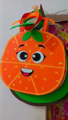 a paper plate with a cartoon orange on it's face and green leaves sticking out of its mouth