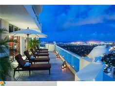 a balcony with chairs and an umbrella overlooking the city lights