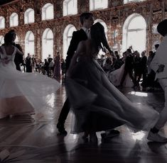 a man and woman are dancing in an old building with many other people around them