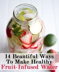 a mason jar filled with sliced strawberries, cucumbers and limes on a white table