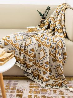 a couch with a blanket on top of it next to a coffee table and plant