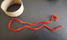 an orange string next to a roll of toilet paper and a white tube on a black surface