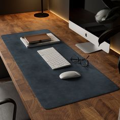 a computer desk with a mouse, keyboard and glasses on it in front of a monitor