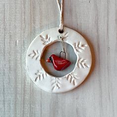 a ceramic ornament with a red bird on it's side hanging from a cord