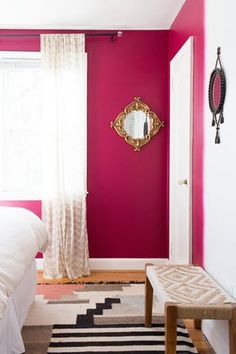 a bedroom with pink walls and white curtains