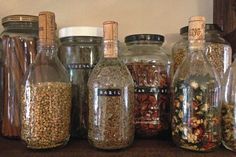 several glass jars filled with different types of grains and spices sitting on a shelf next to each other