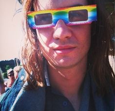 a man with long hair wearing sunglasses and looking at the camera