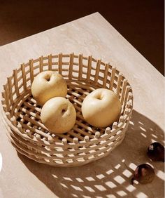 three apples in a basket on a table