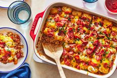 a casserole dish with meat and vegetables in it next to two bowls of water