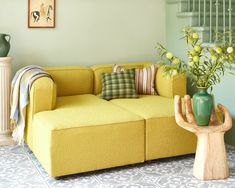 a living room with yellow couches and green vases