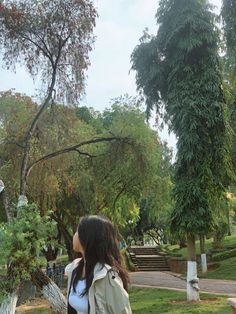 a woman standing next to a tree in a park