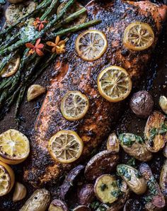 salmon, asparagus and potatoes on a baking sheet with lemons for garnish