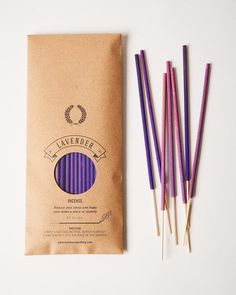 four purple and yellow toothbrushes sitting next to a brown paper bag on a white surface