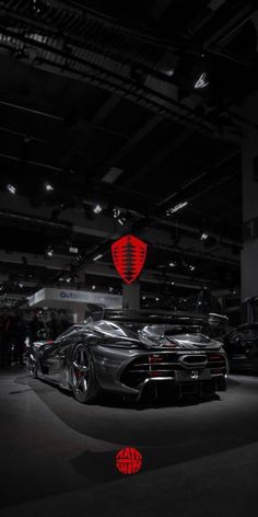 a black and white photo of a car in a showroom with people looking at it