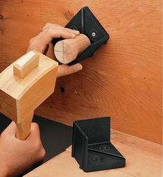 a person holding a piece of wood in front of a wooden object on the wall