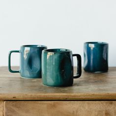 three coffee mugs sitting on top of a wooden table