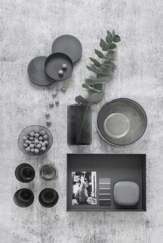 black and white photograph of various items on table with plant in vase, bowl, plates