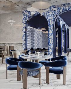 a dining room with blue and white wallpaper, chairs and tables in the center