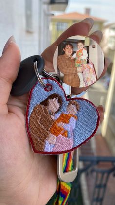 a hand holding a keychain with an image of a man and woman on it