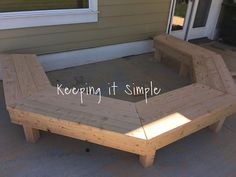 a wooden bench sitting on top of a cement ground next to a house with the words keeping it simple