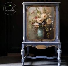 an old cabinet with flowers painted on the front and sides, sitting in a dark room