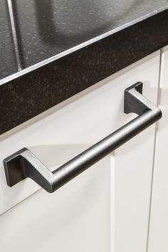 a black handle on a white cabinet door