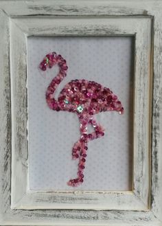 a pink flamingo is in a white frame with some sequins on it