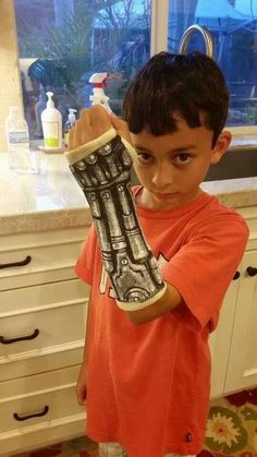 a young boy holding up an oven mitt