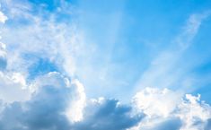 the sky is filled with white clouds and blue skies are in the foreground, as well as bright sunbeams