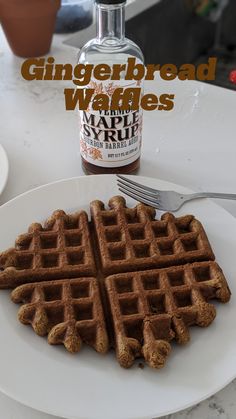 a white plate topped with waffles next to a bottle of gingerbread syrup