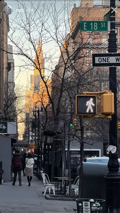 people are walking down the street in front of some tall buildings and one has a pedestrian crossing sign