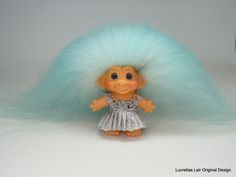 a troll doll with blue hair and silver dress