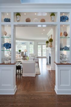 an open kitchen and dining room area with white cabinets, wood flooring and blue vases on the shelves