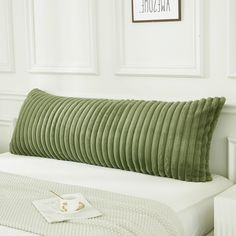 a green pillow on top of a white bed