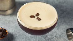 a drink in a wine glass with coffee beans on the rim