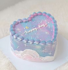 a birthday cake with stars and clouds on it sitting on top of a white blanket