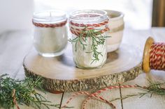 two mason jars with sprigs and twine tied around them on a wooden board