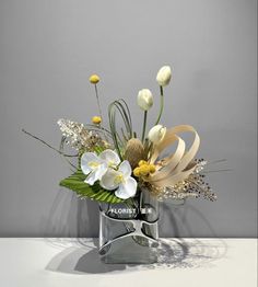 a vase filled with white flowers on top of a table next to a gray wall