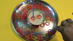 a person using scissors to cut red and yellow paper clips on a metal platter