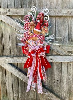 a christmas wreath with candy canes and a gingerbread man on it hanging from a wooden fence