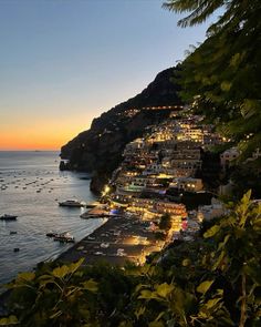 the sun is setting over an ocean with boats in the water and buildings on the hillside