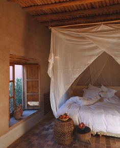 a bed with white sheets and pillows in a room next to a window that looks out onto the outdoors