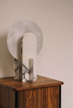 a marble sculpture sitting on top of a wooden cabinet next to a white plate and silver object