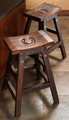 two wooden stools sitting next to each other on a tile floor in front of a counter