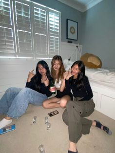 three young women sitting on the floor with bottles and water in front of their faces