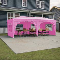 a pink tent set up in front of a house with tables and chairs under it